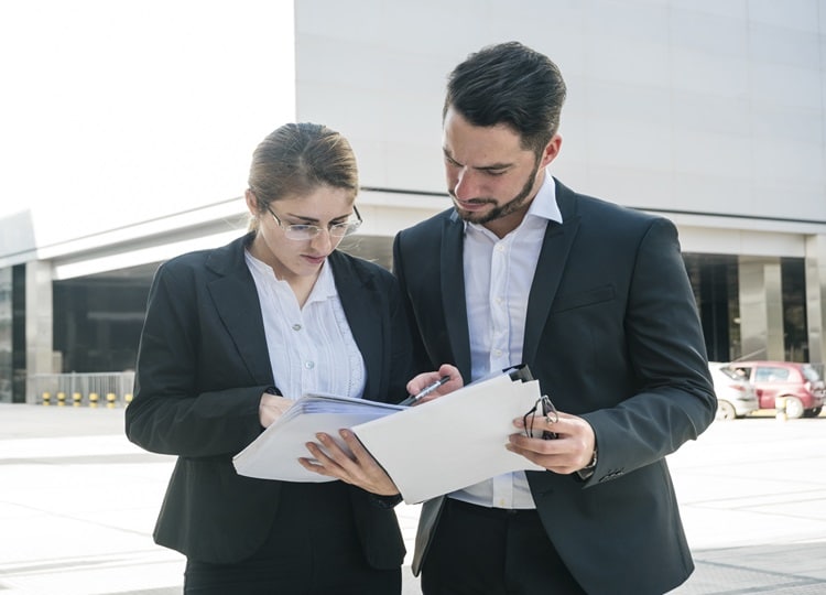 businessman-businesswoman-checking-documents-outdoors